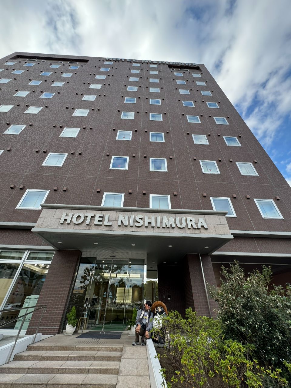 ด้านหน้าโรงแรม HOTEL NISHIMURA อาคารโมเดิร์นสูงหลายชั้น พร้อมตัวเลือกห้องพักแบบฟูจิวิวสำหรับชมภูเขาฟูจิ