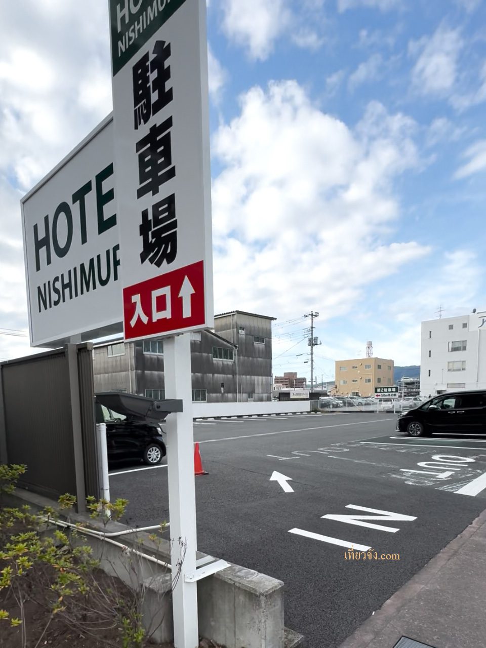 ภาพป้ายทางเข้าที่จอดรถของ HOTEL NISHIMURA ใน Fujinomiya มีป้ายภาษาญี่ปุ่นเขียนว่า '駐車場' (ที่จอดรถ) และมีรถยนต์จอดอยู่